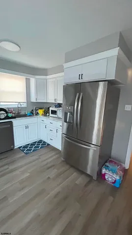 a kitchen with granite countertop a refrigerator and wooden floor