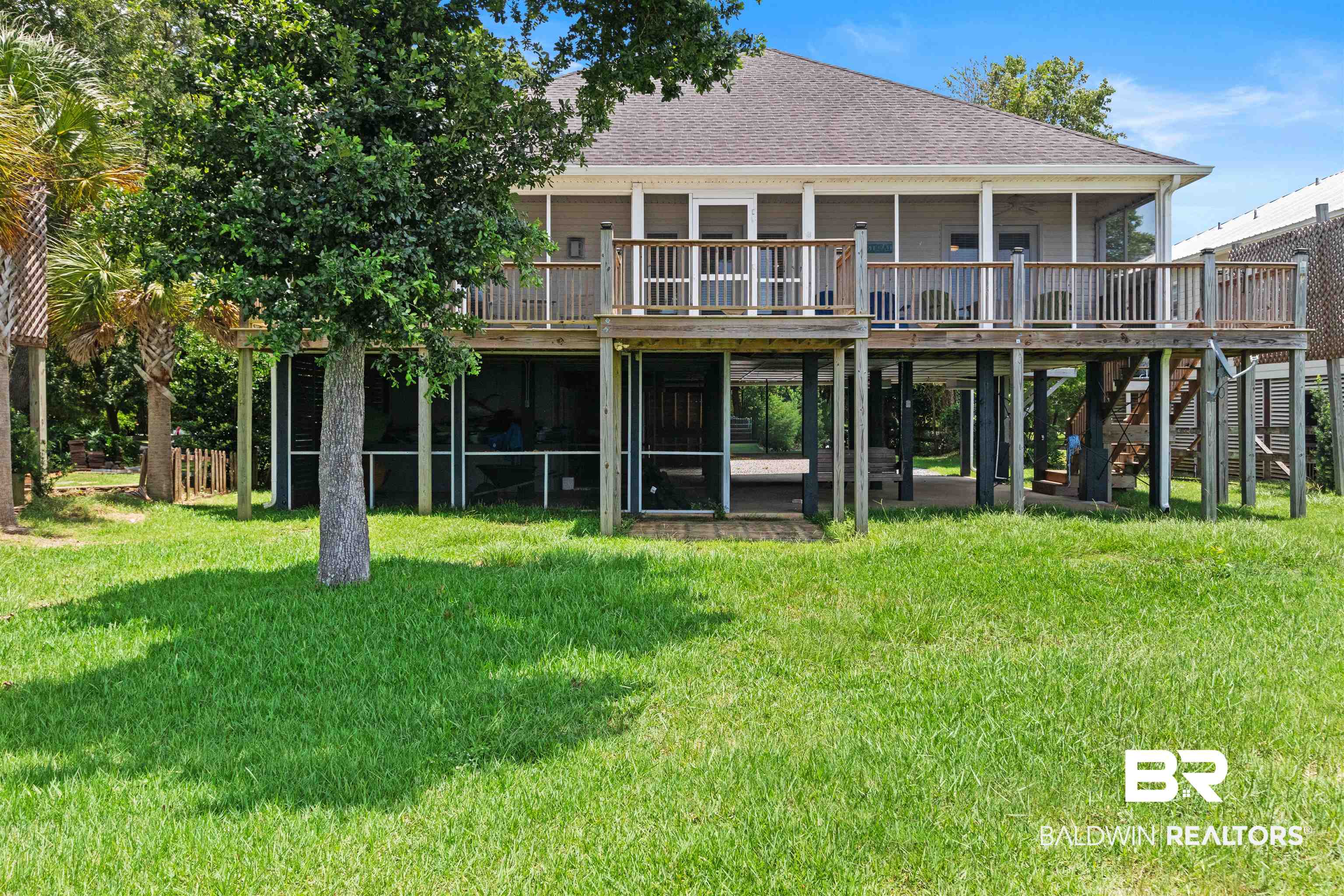 9581 South Bay Street Foley, AL 36535 - Photo 29 of 44 Elevated residence featuring a screened lower patio, a covered upper deck with wood railings, a shingled roof, and a grassy yard