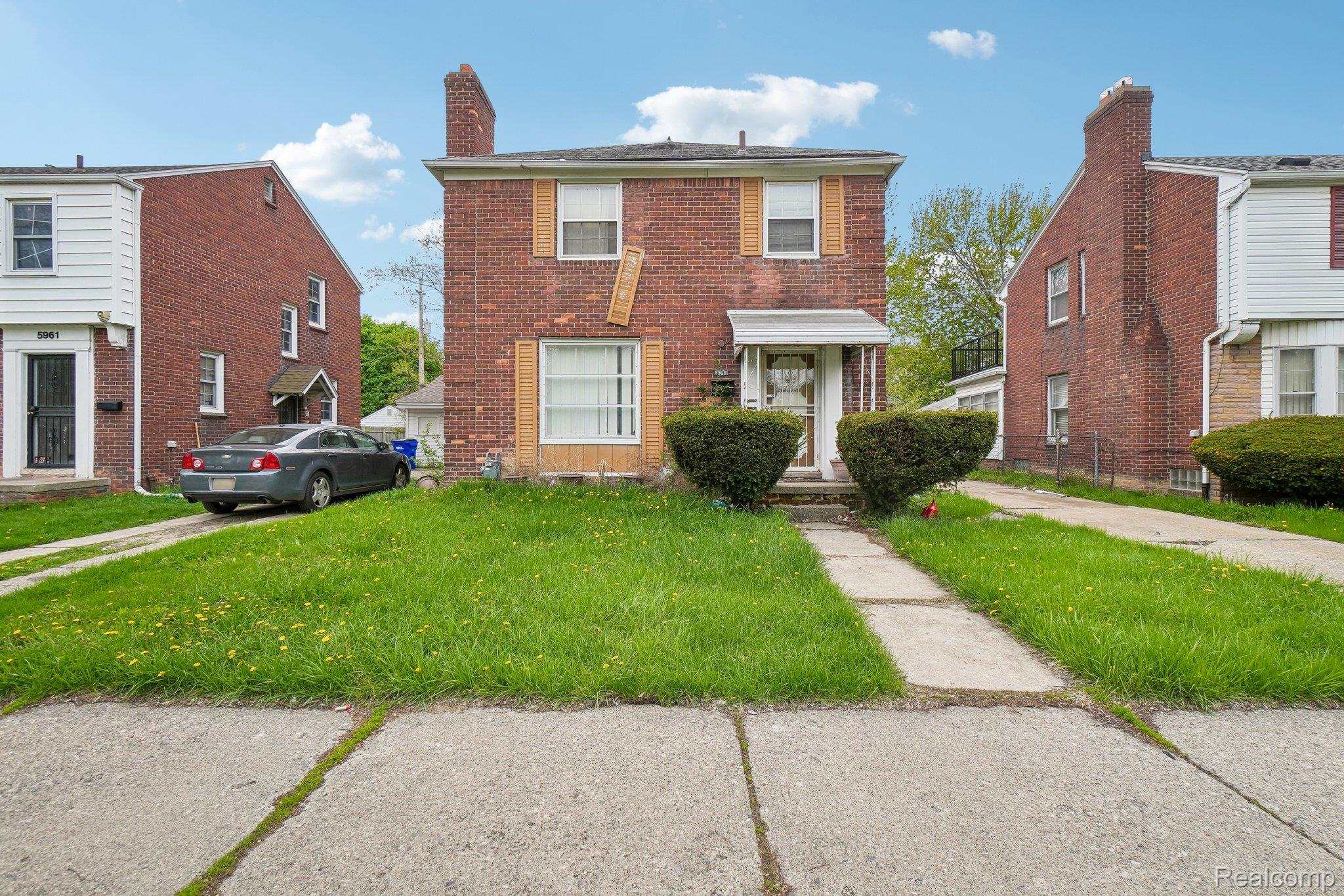 Traditional-style home featuring a front yard, a chimney, and brick siding