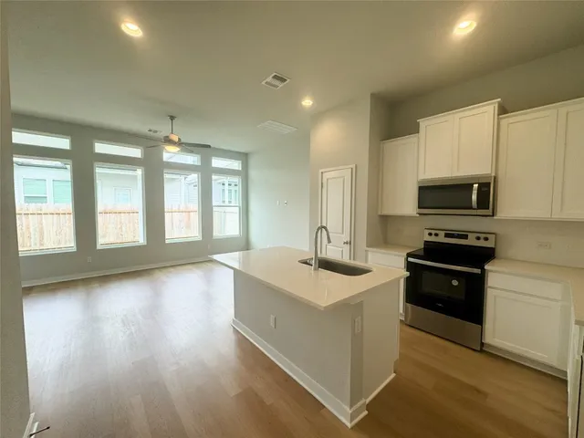 a view of a kitchen counter top space stainless steel appliances and windows