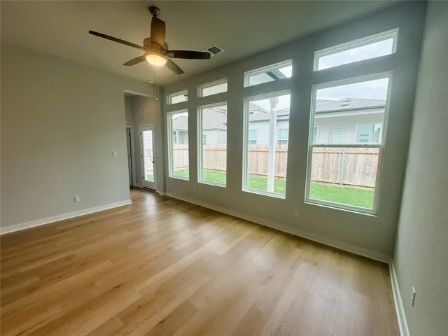 a view of an empty room with wooden floor and a window