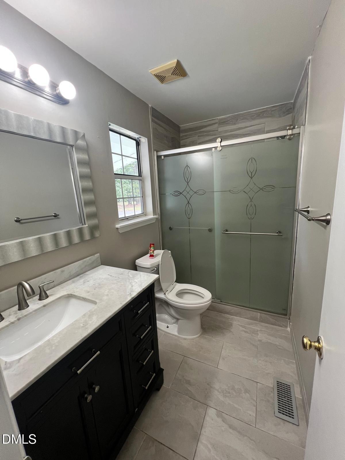 1111 Penzance Avenue Durham, NC 27704 - Photo 14 of 18 a bathroom with a sink a toilet a mirror and shower