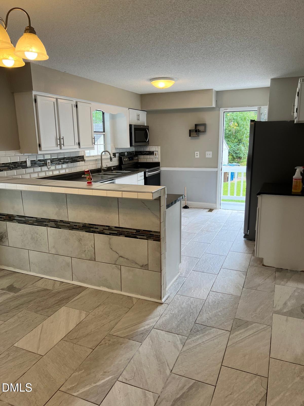 1111 Penzance Avenue Durham, NC 27704 - Photo 5 of 18 a large kitchen with kitchen island a sink a counter and a stove top oven