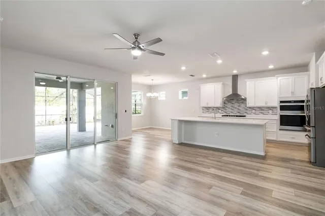 a view of an empty room and kitchen with wooden floor