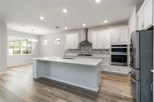 a large kitchen with stainless steel appliances a large counter top a stove and a refrigerator