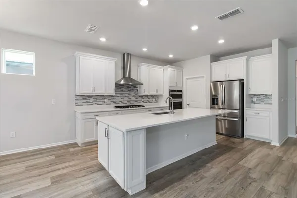 a kitchen with stainless steel appliances kitchen island granite countertop a refrigerator and a stove top oven