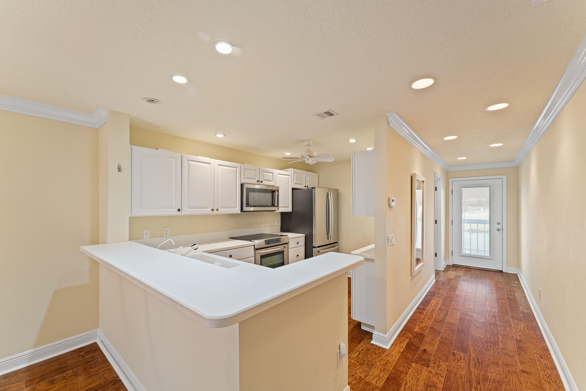 10 Northeast Plantation Road, Unit 305 Jensen Beach, FL 34957 - Photo 11 of 48 a kitchen that has a lot of white cabinets and wooden floor