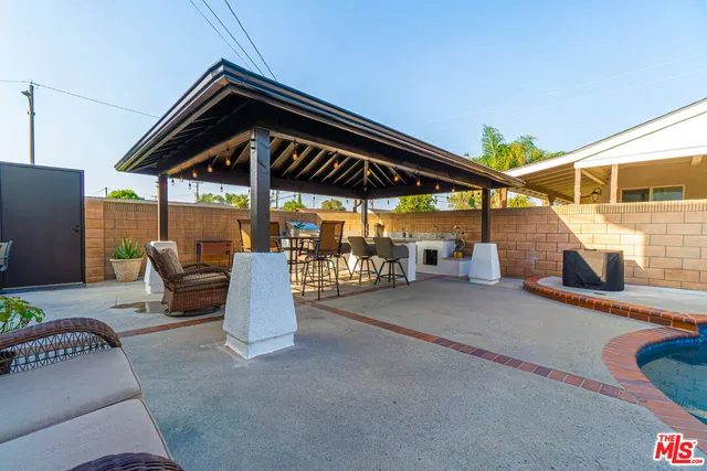a swimming pool with barbeque oven table and chairs