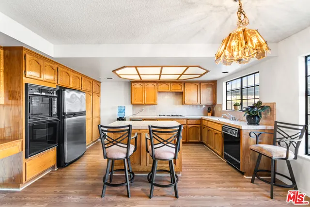a kitchen with stainless steel appliances granite countertop a kitchen island hardwood floor and a sink