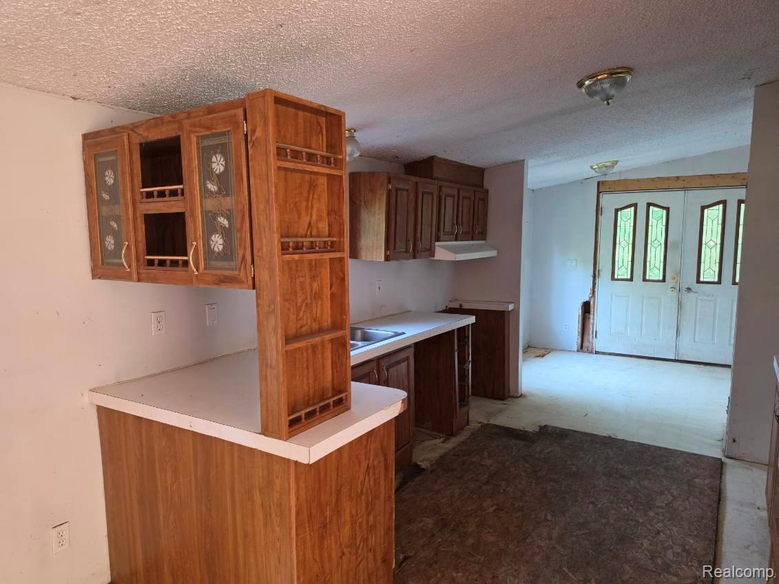 3897 Swaffer Road Millington, MI 48746 - Photo 5 of 16 Kitchen featuring wood-finish cabinetry with glass paneling, laminate countertops, and a built-in sink