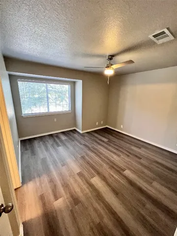 an empty room with wooden floor fan and windows