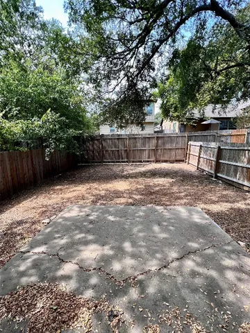 a view of a backyard with large trees and wooden fence