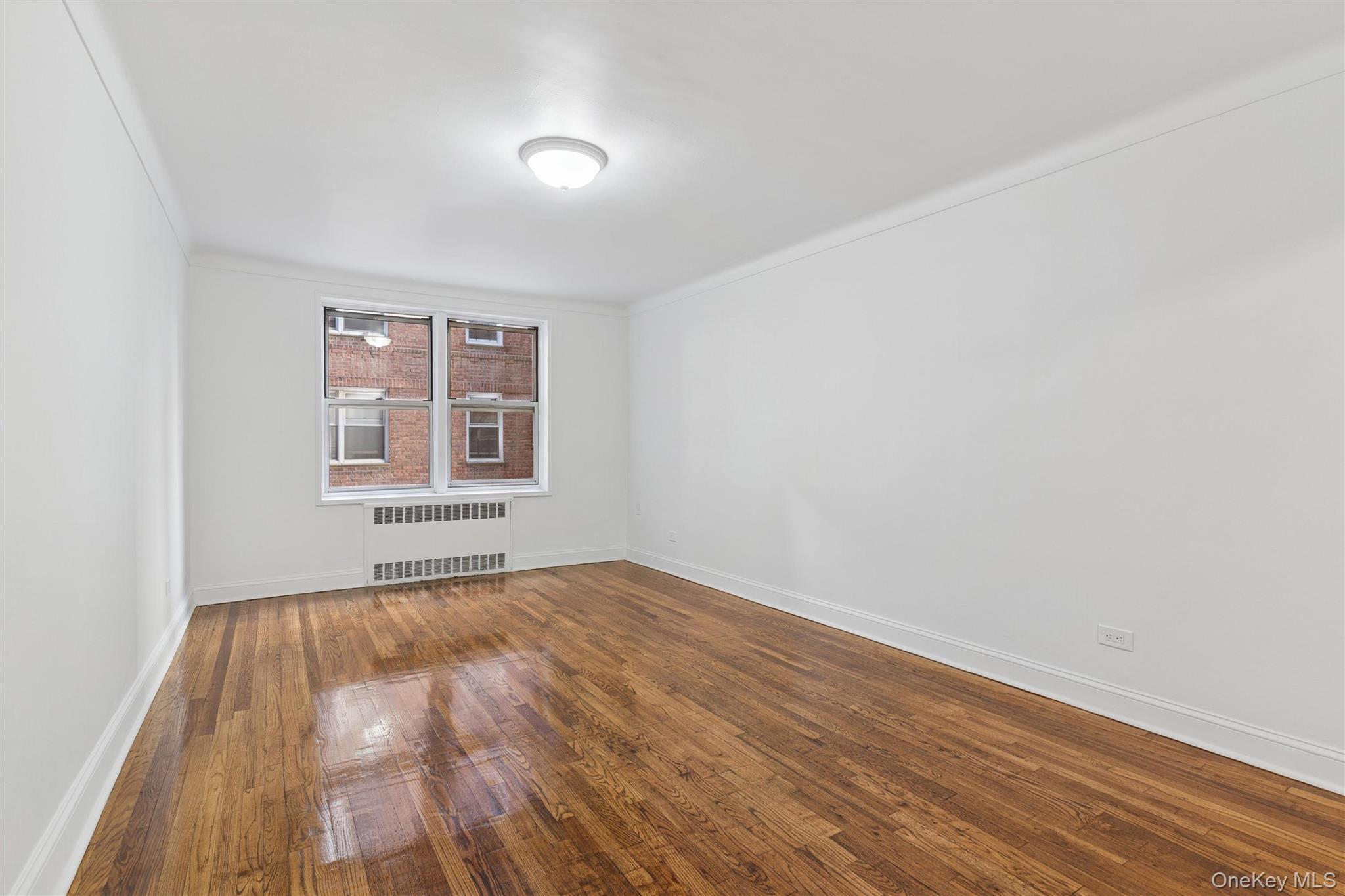 67-12 Yellowstone Boulevard, Unit B16 Queens, NY 11375 - Photo 12 of 15 Spare room with wood-type flooring, radiator, and crown molding