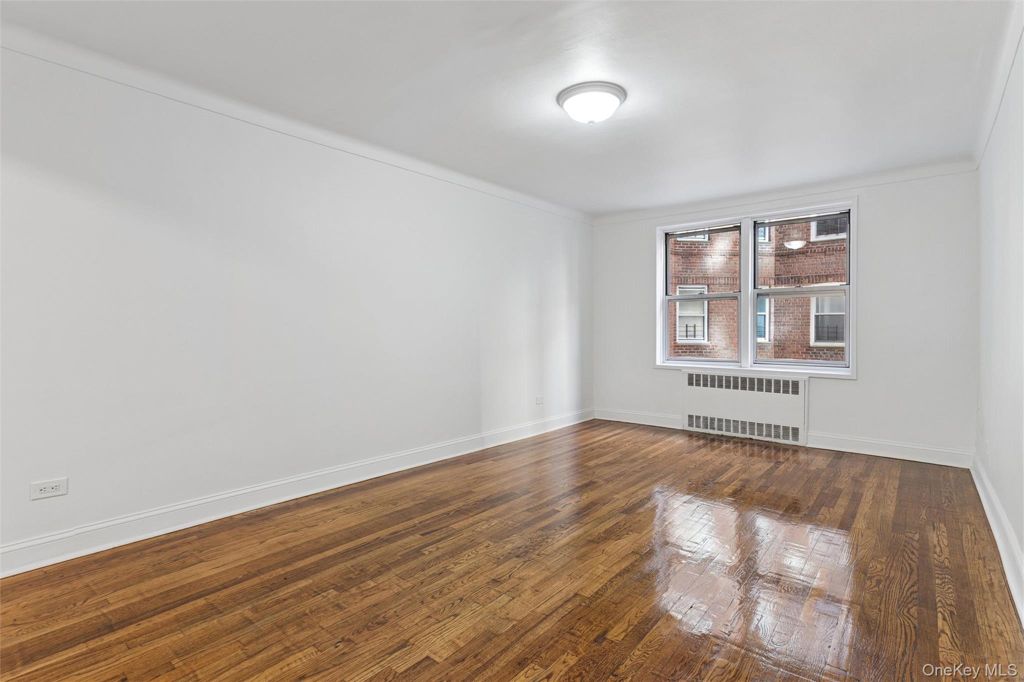 67-12 Yellowstone Boulevard, Unit B16 Queens, NY 11375 - Photo 13 of 15 Unfurnished room with wood finished floors, radiator heating unit, and ornamental molding