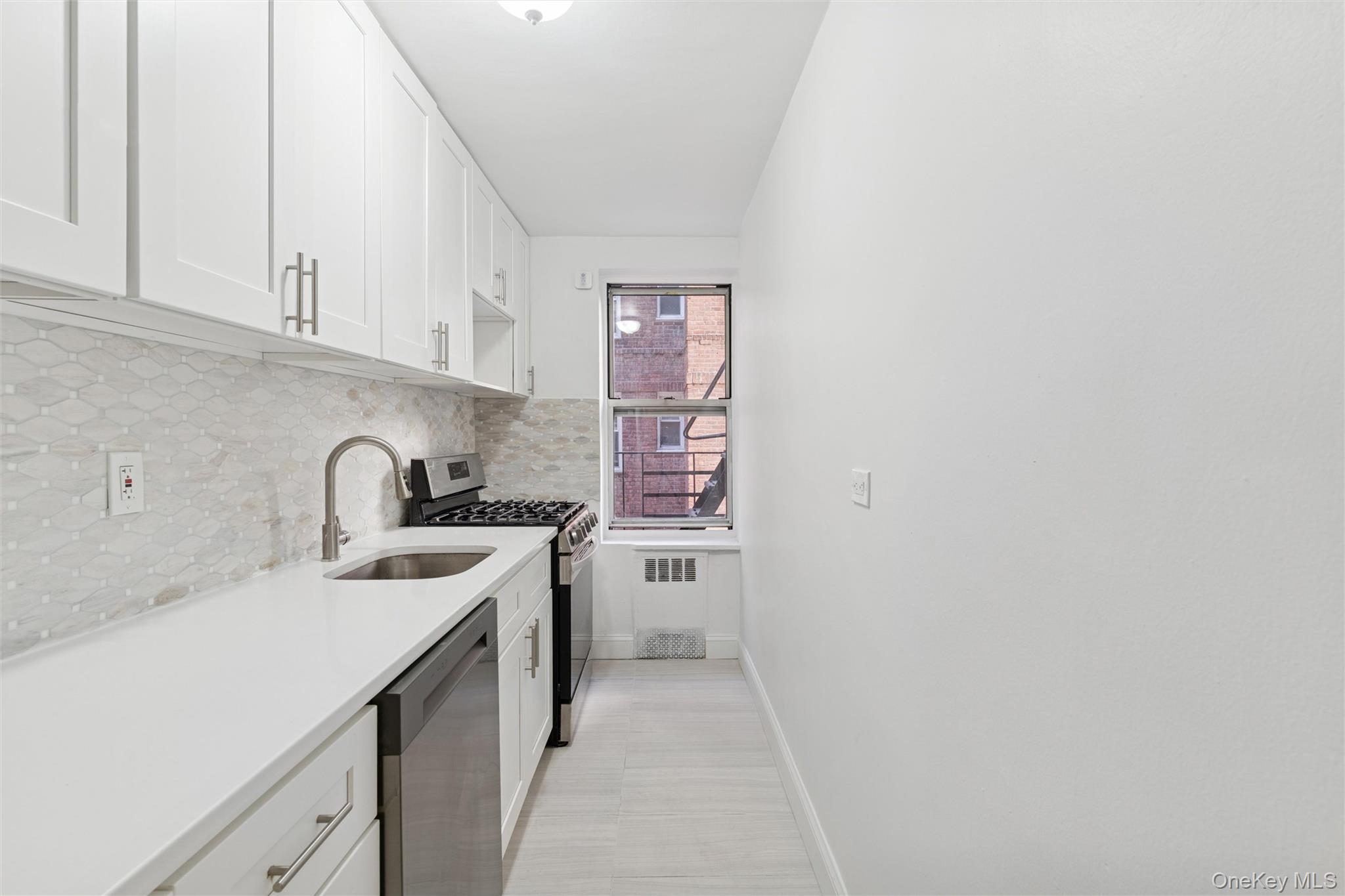 67-12 Yellowstone Boulevard, Unit B16 Queens, NY 11375 - Photo 8 of 15 Kitchen with stainless steel appliances, decorative backsplash, white cabinetry, light stone countertops, and open shelves