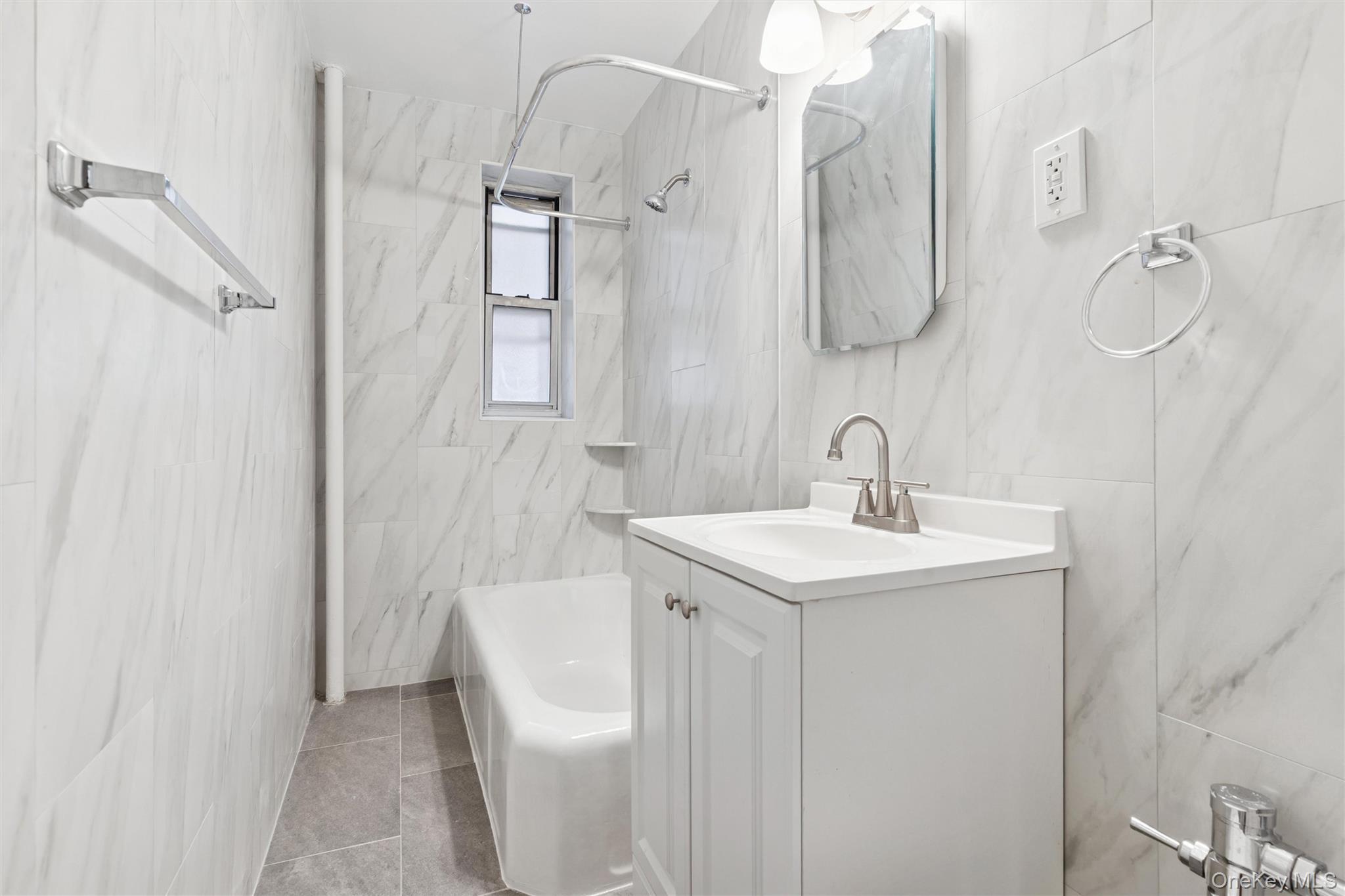 67-12 Yellowstone Boulevard, Unit B16 Queens, NY 11375 - Photo 10 of 15 Full bathroom with tile walls, vanity, shower / washtub combination, and light tile patterned floors