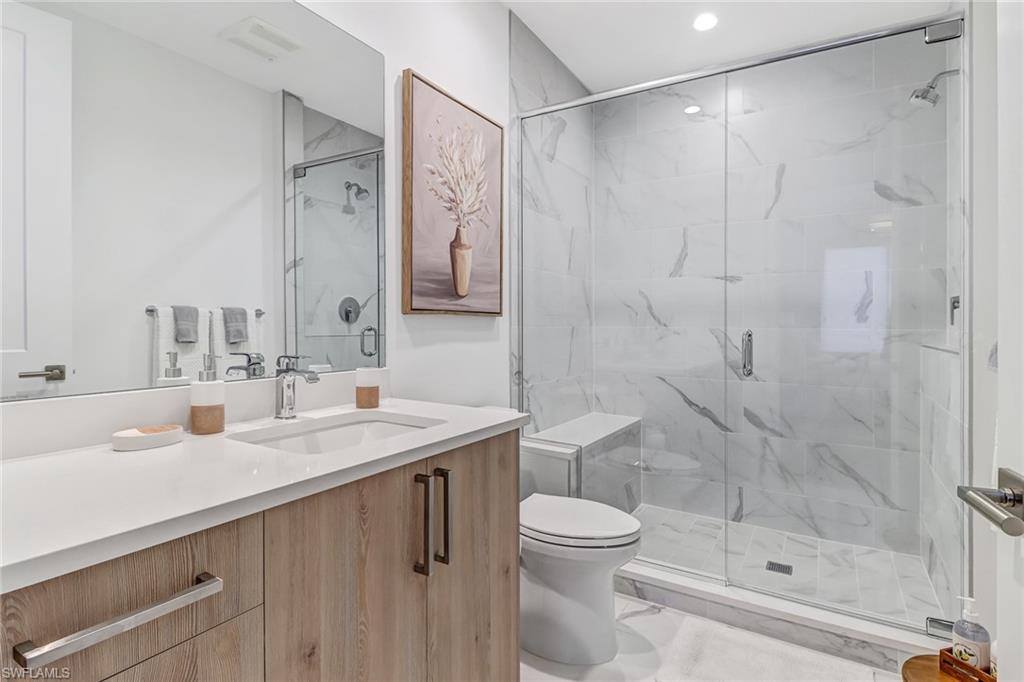 1115 Central Avenue, Unit 340 Naples, FL 34102 - Photo 16 of 39 a bathroom with a shower sink vanity mirror and toilet