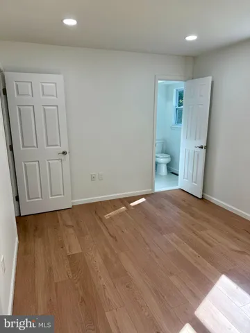 a view of an empty room with wooden floor and closet