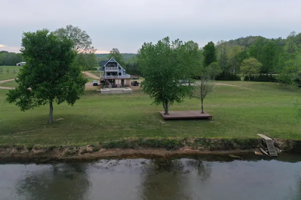 a view of a lake with a yard and large trees