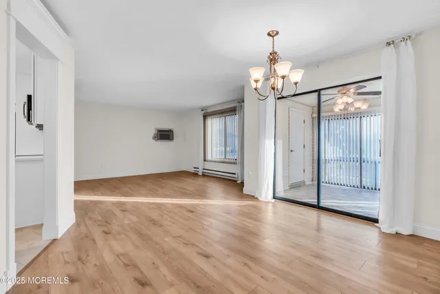 an empty room with wooden floor staircase and windows
