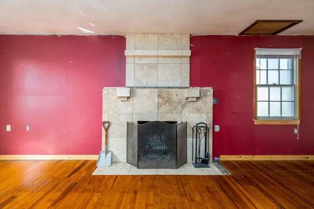 a view of empty room with fireplace and wooden floor