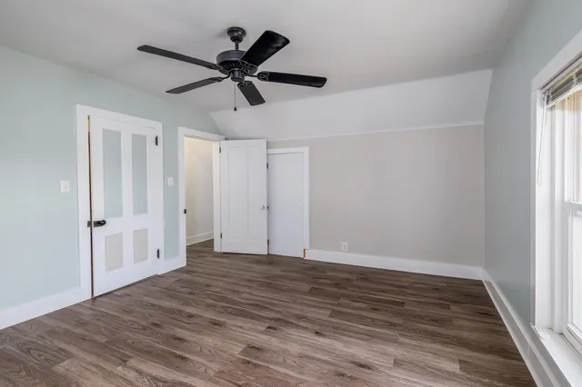 a view of empty room with wooden floor and ceiling fan