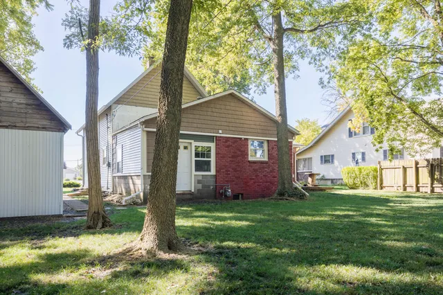 a view of a brick house with a yard and large tree