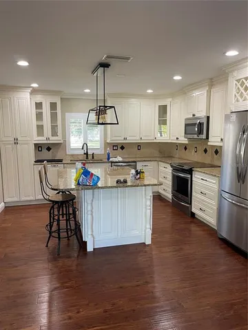 a kitchen with stainless steel appliances granite countertop a table chairs stove and refrigerator