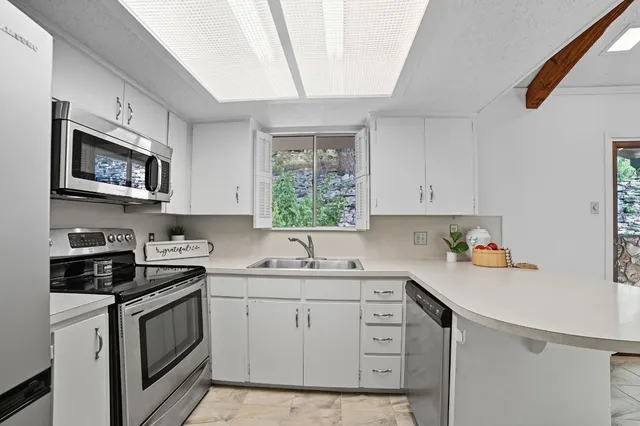 a kitchen with a sink white cabinets and white appliances