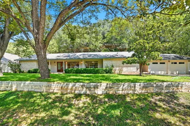 a front view of a house with a yard and potted plants