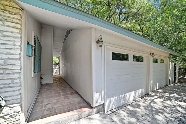 a view of a patio with table and chairs under an umbrella with large trees