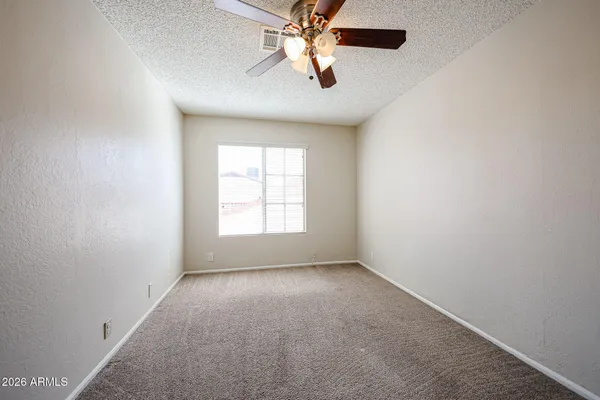an empty room with closet and a chandelier fan