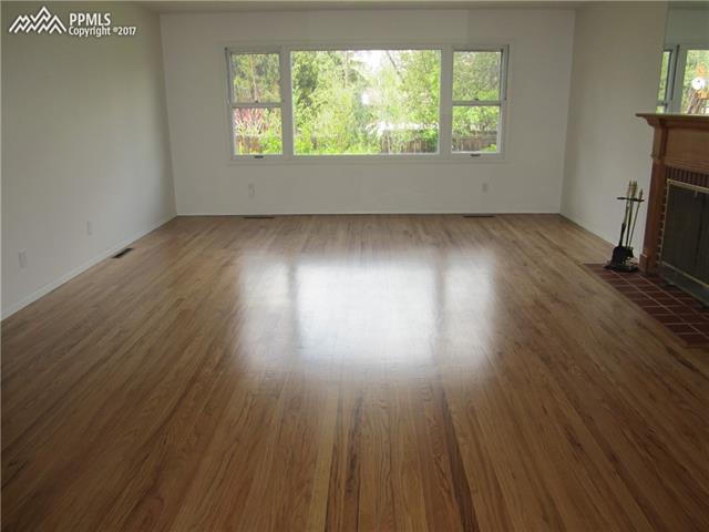 823 Cresta Road Colorado Springs, CO 80905 - Photo 5 of 36 Great Room features beautiful original hardwood floors, wood burning fireplace, and large picture window overlooking the backyard.