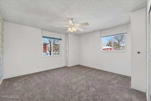 an empty room with windows and fan