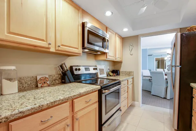 a kitchen with granite countertop stainless steel appliances a sink a stove and cabinets