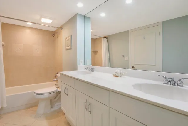 a bathroom with a granite countertop sink a toilet and a large mirror