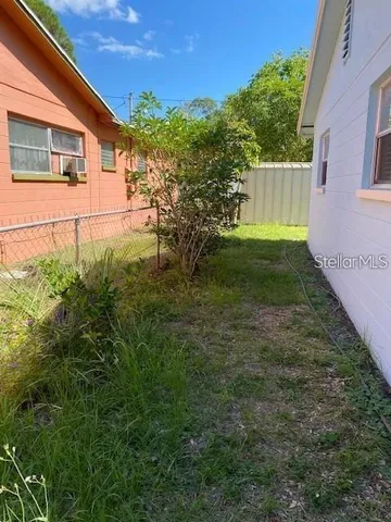 a backyard of a house with plants and large tree