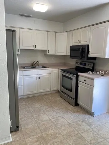 a kitchen with stainless steel appliances granite countertop a stove a sink and a microwave