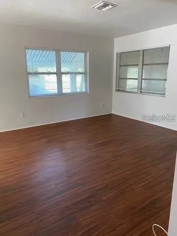 an empty room with wooden floor and windows
