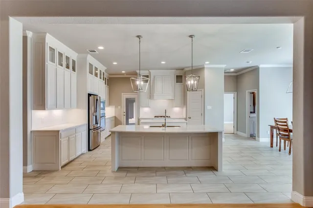 a large white kitchen with a sink and refrigerator