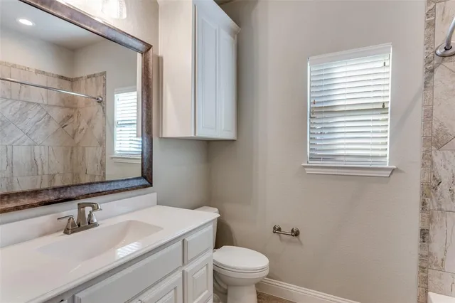 a bathroom with a granite countertop sink toilet a mirror and window