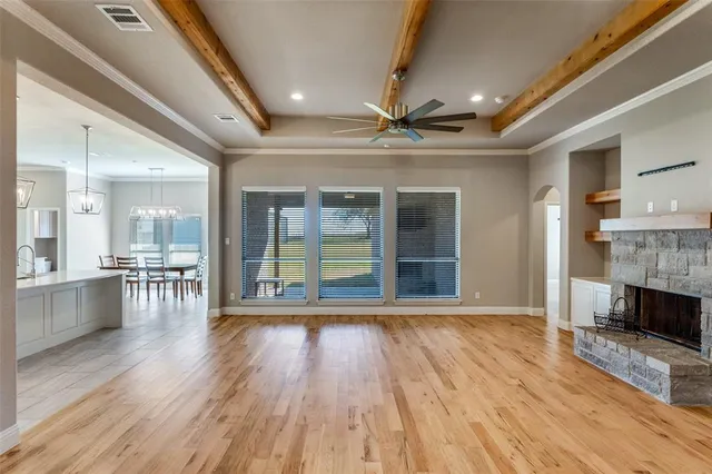a view of an empty room with wooden floor and a fireplace