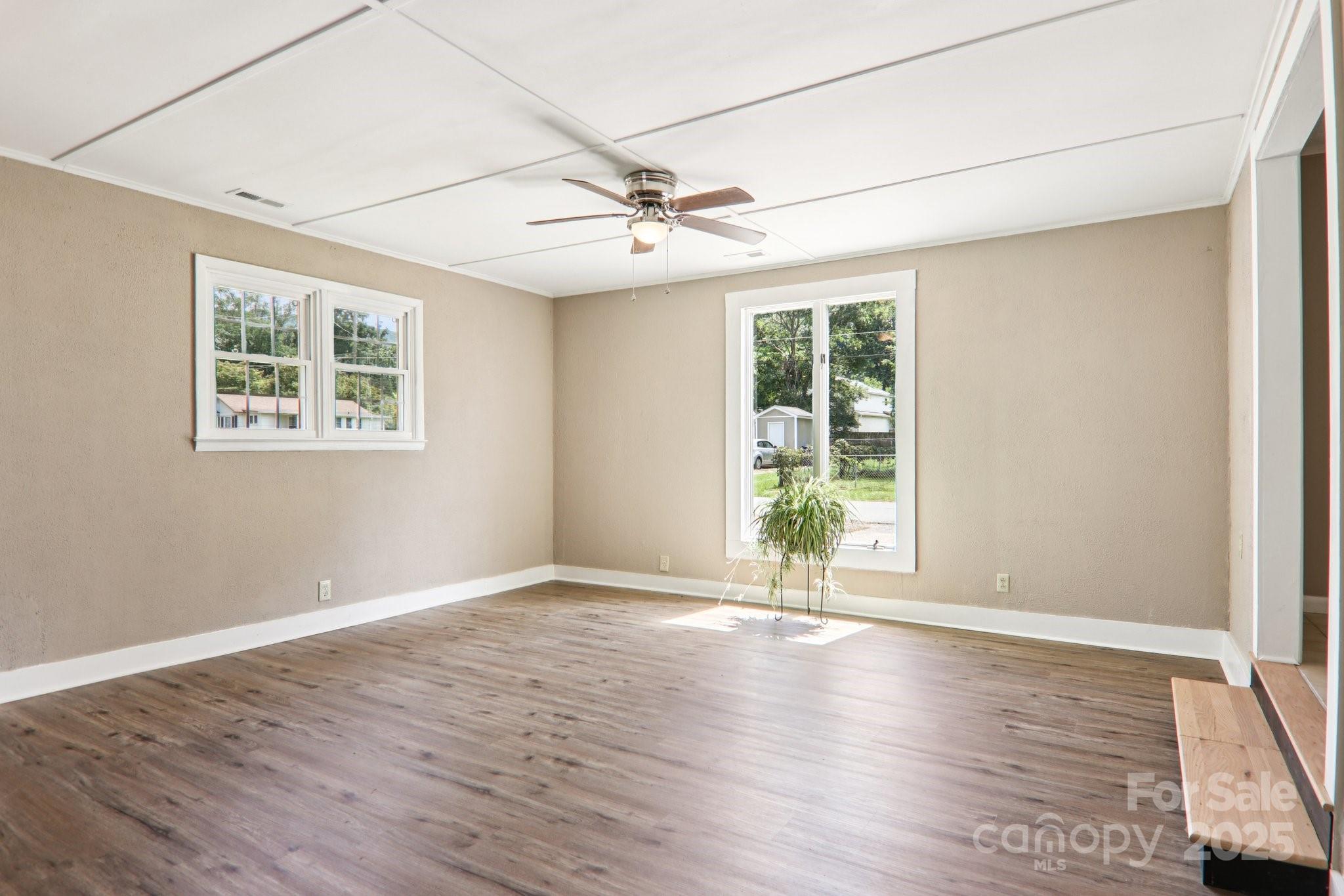 55 Polk Street Waynesville, NC 28786 - Photo 21 of 44 an empty room with wooden floor ceiling fan and windows