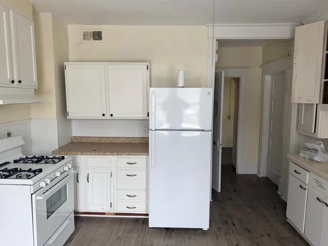 a kitchen with cabinets appliances and wooden floor