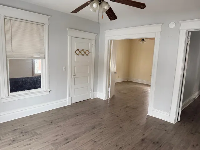 an empty room with wooden floor cabinet and windows
