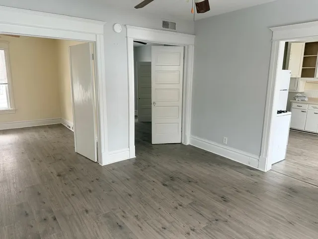 an empty room with wooden floor & windows and bathroom