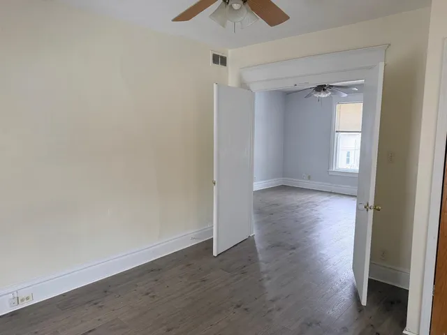 an empty room with wooden floor and a ceiling fan