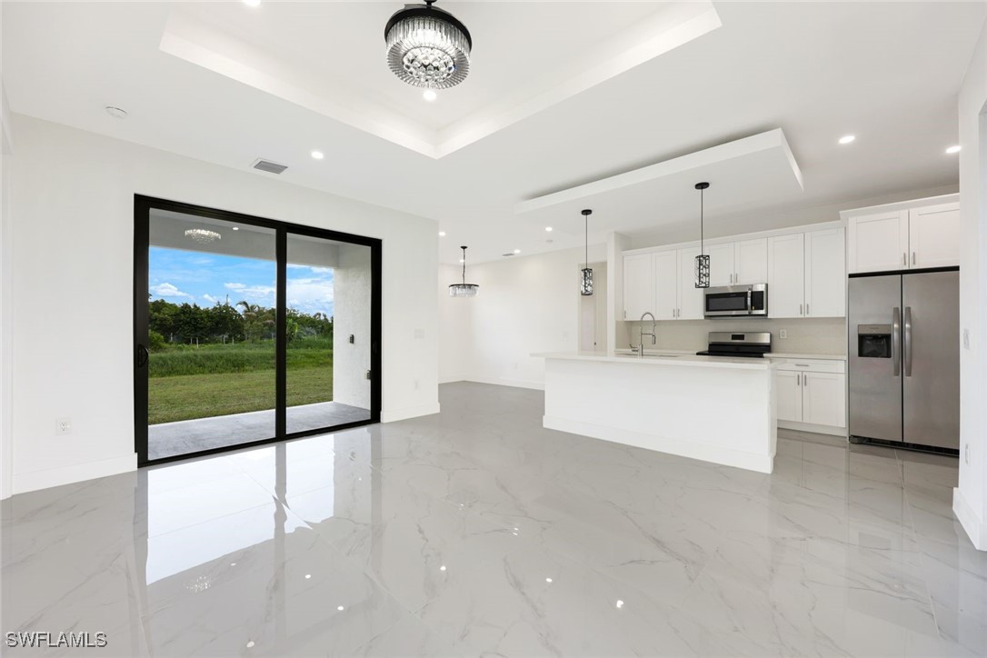 147 Partridge Street Lehigh Acres, FL 33974 - Photo 4 of 20 a view of kitchen with stainless steel appliances granite countertop a stove top oven a refrigerator with white cabinets and wooden floor