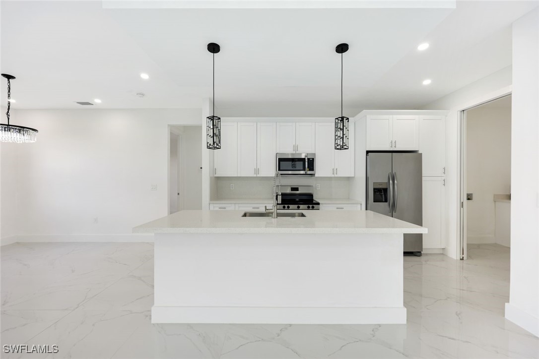 147 Partridge Street Lehigh Acres, FL 33974 - Photo 9 of 20 a kitchen with stainless steel appliances a refrigerator sink and microwave