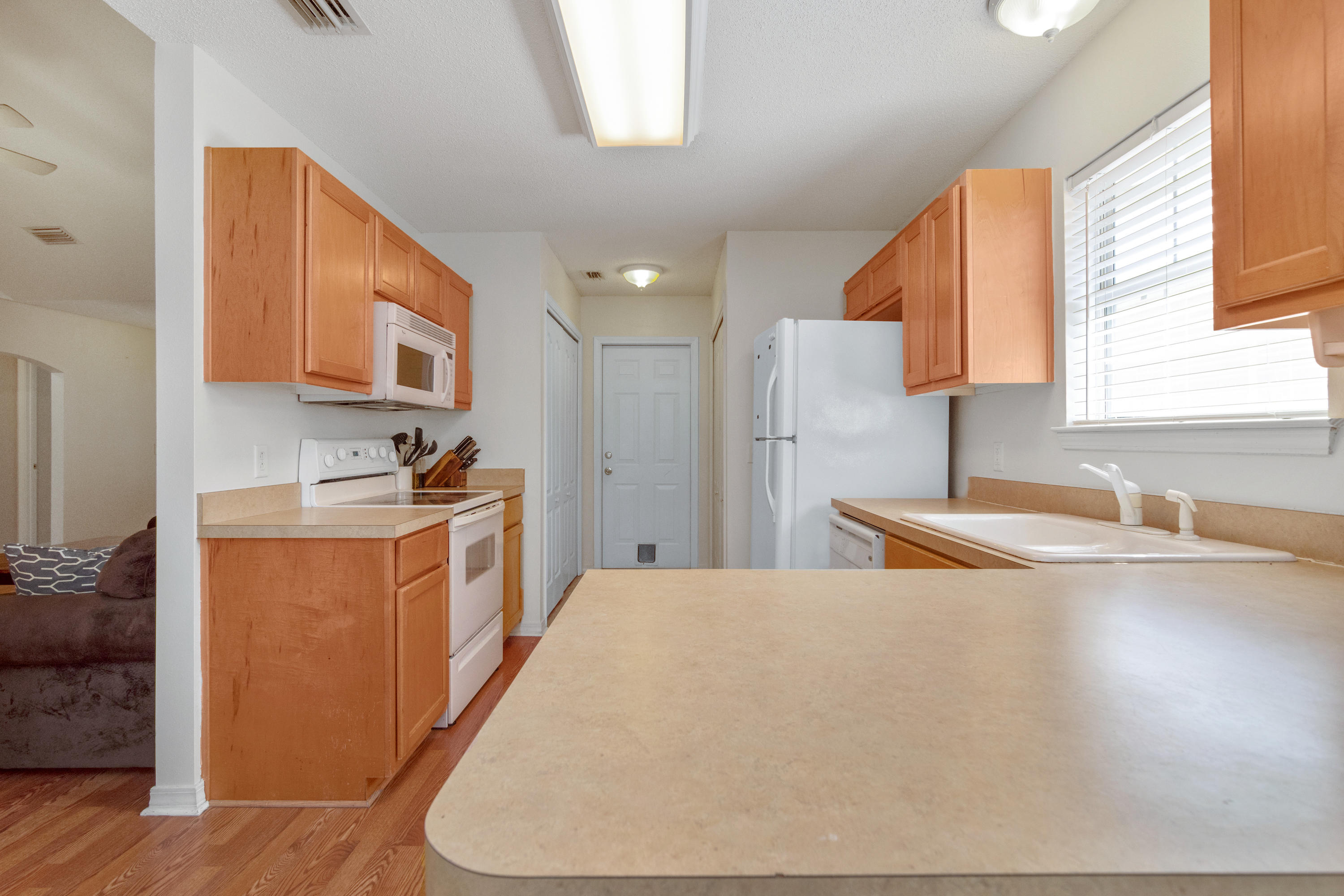 1845 Brick Circle Fort Walton Beach, FL 32547 - Photo 5 of 24 a kitchen with stainless steel appliances a refrigerator a sink a stove and white cabinets with wooden floor